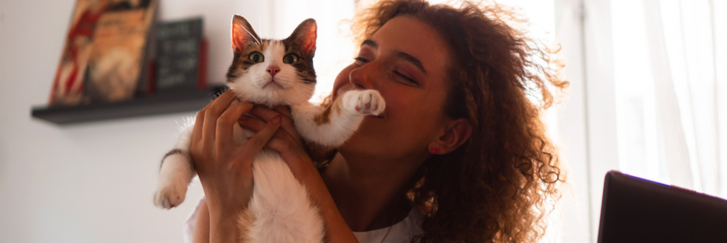 A woman holding up her kitten and smiling